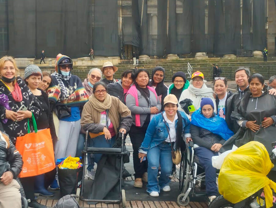 Grupo grande de personas, varias en silla de ruedas, reunidas en una plaza