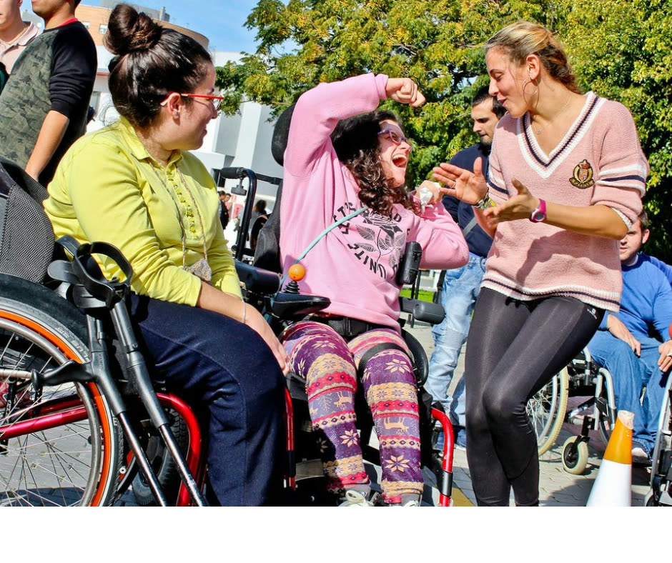 Mujeres en silla de ruedas conversan y ríen durante un encuentro al aire libre